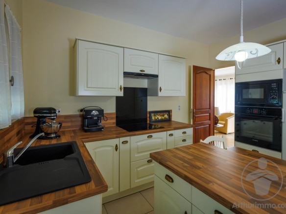 Modern kitchen with wooden furniture and integrated appliances.