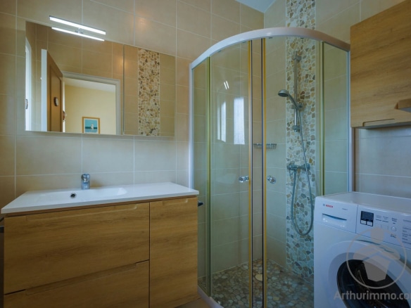 Modern bathroom with shower, wooden furniture and washing machine.