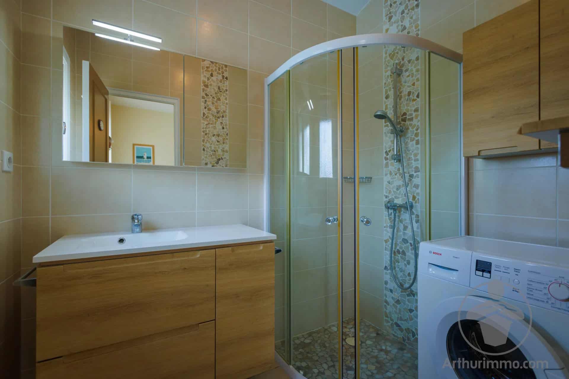 Modern bathroom with shower, wooden furniture and washing machine.