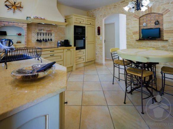 Interior of a spacious kitchen with wooden furniture and a large marble worktop.