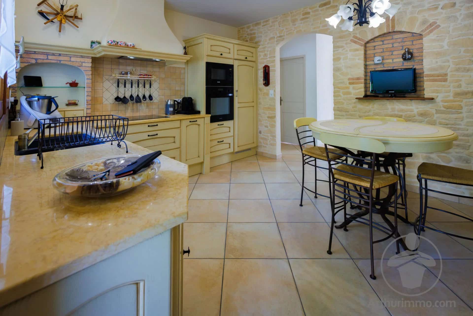 Interior of a spacious kitchen with wooden furniture and a large marble worktop.