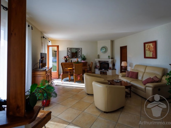 Interior of a house with a bright living room and dining area, modern furniture and a fireplace.