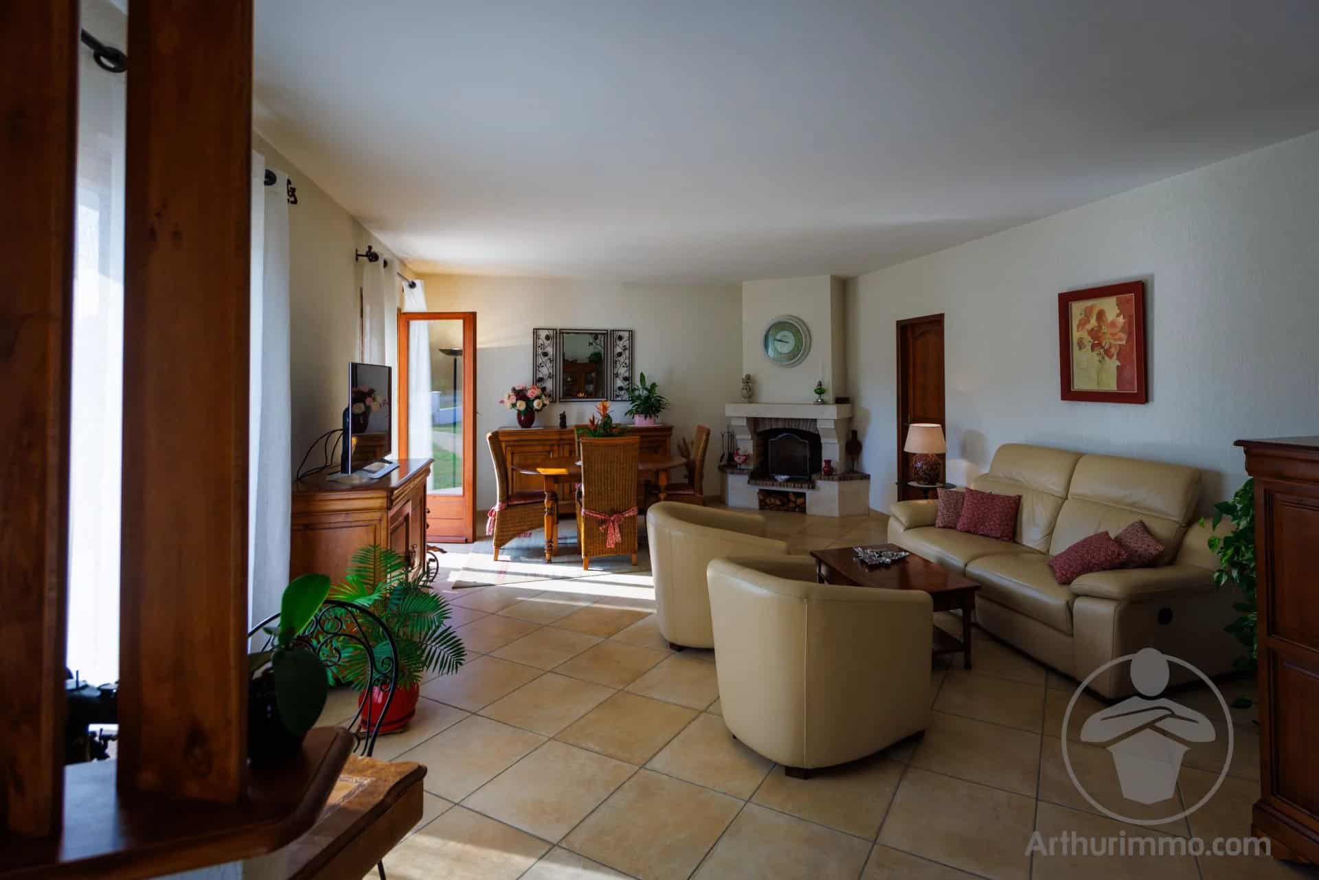 Interior of a house with a bright living room and dining area, modern furniture and a fireplace.