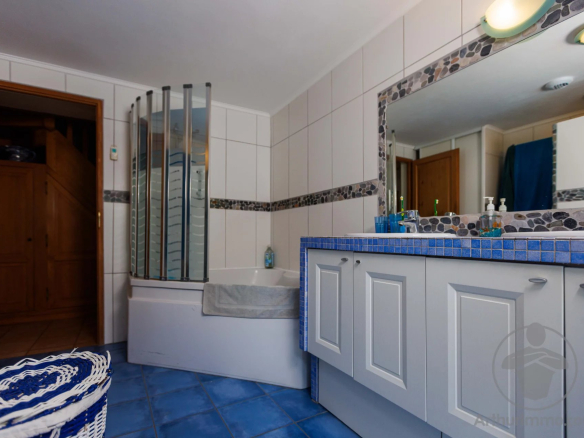 Modern bathroom with bathtub, shower and vanity unit, blue tiles.