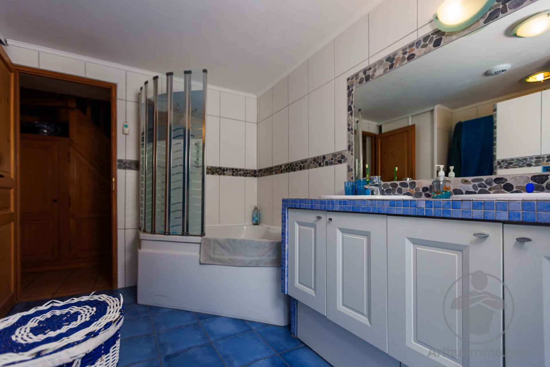 Bathroom in a property in the Landes region Modern bathroom with bathtub, shower and vanity unit, blue tiles.