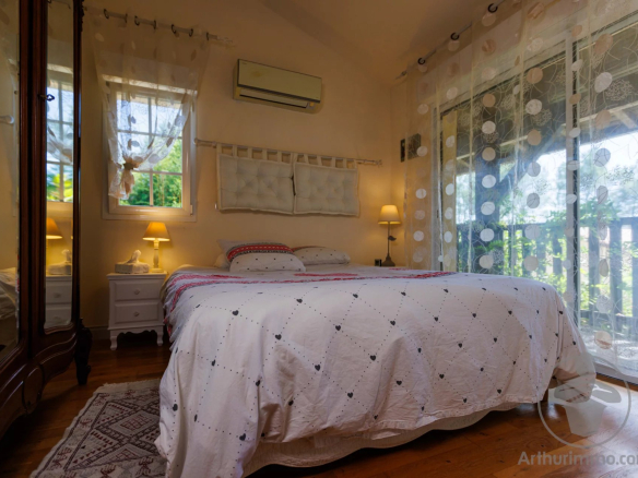 Guest room with double bed and warm decor, windows letting in light.