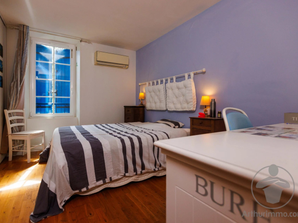 Guest room with double bed and simple decor, window letting in light.