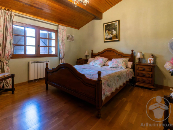 Chambre d'une maison familiale à Biscarrosse Plage avec lit en bois et décoration florale.