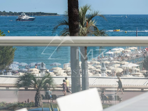 Beachside resort with rows of beige umbrellas and sun loungers along a boardwalk by the blue sea