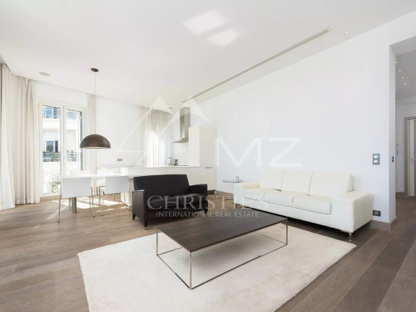 Bright open-plan living room with white sofa, black armchair, and minimalist coffee table on a cream rug