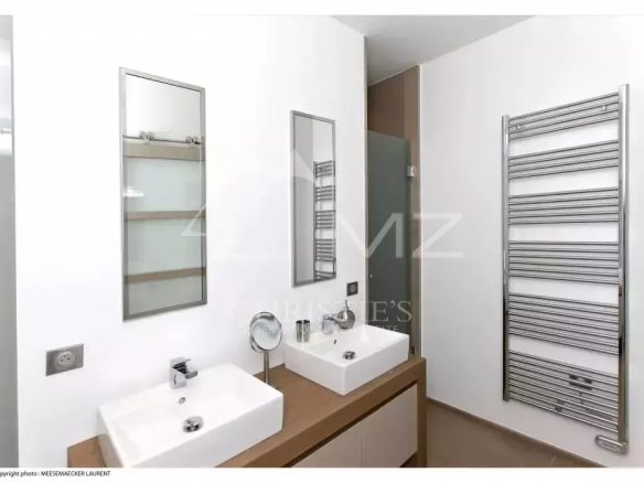Modern bathroom with double rectangular sinks on a wooden vanity, two mirrors, and a chrome towel warmer.