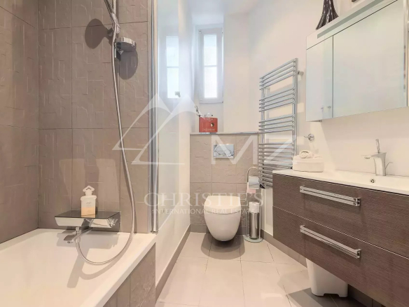 Modern bathroom with glass shower enclosure, edge-lit tub, and a dark wood vanity with two drawers.