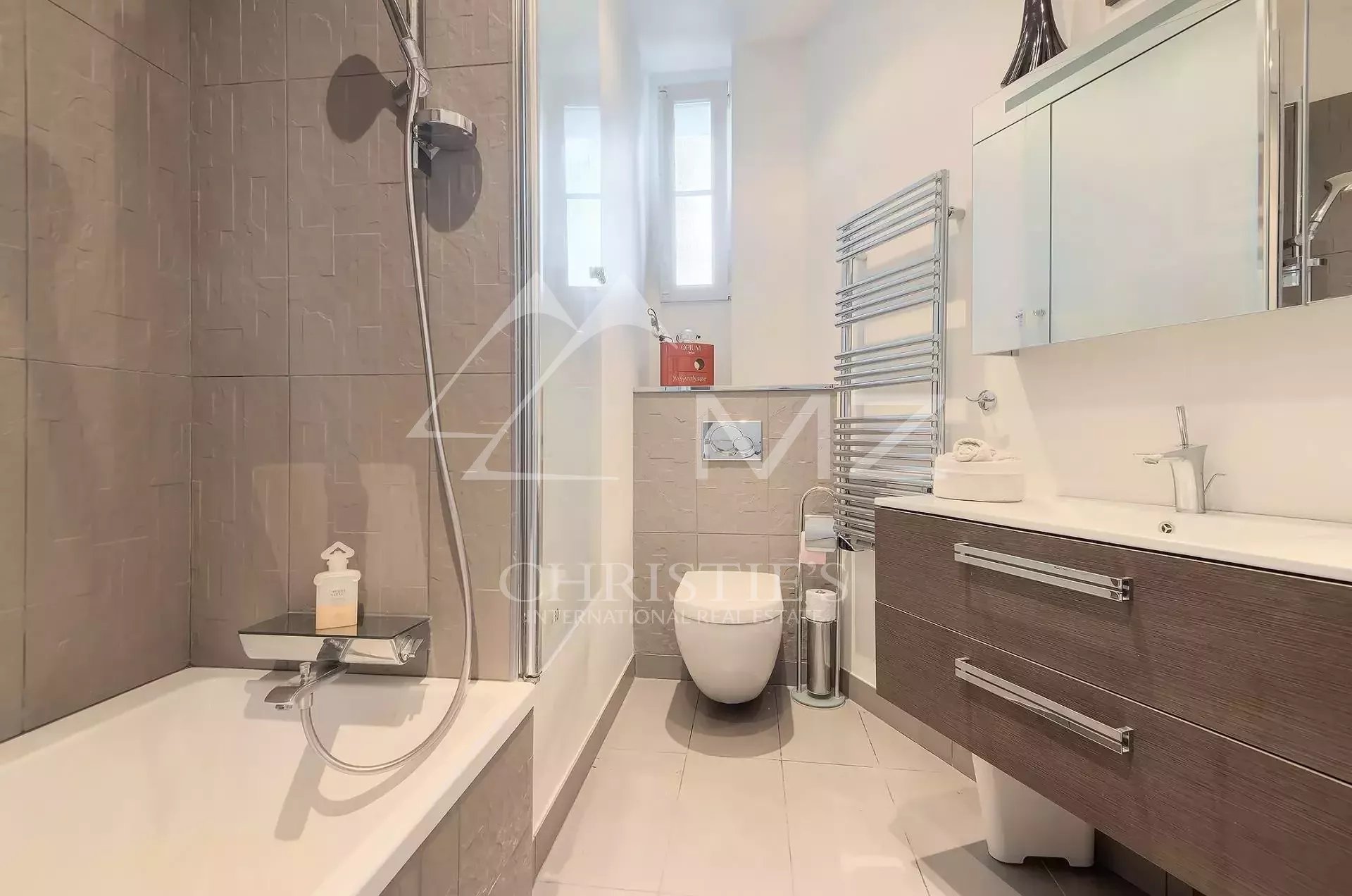Modern bathroom with glass shower enclosure, edge-lit tub, and a dark wood vanity with two drawers.