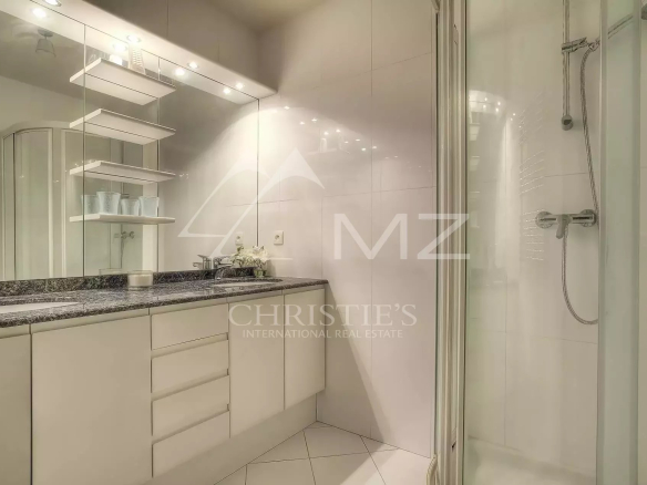 Modern white bathroom with a granite countertop vanity, large mirror, and glass shower enclosure on the right.