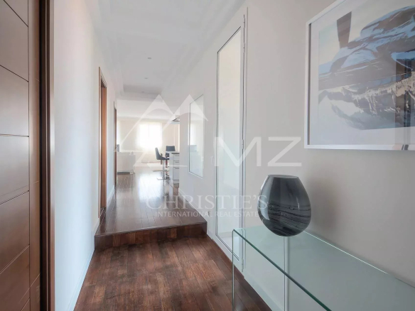 Bright hallway with dark wood floor, glass console table, and a framed landscape print along the wall.