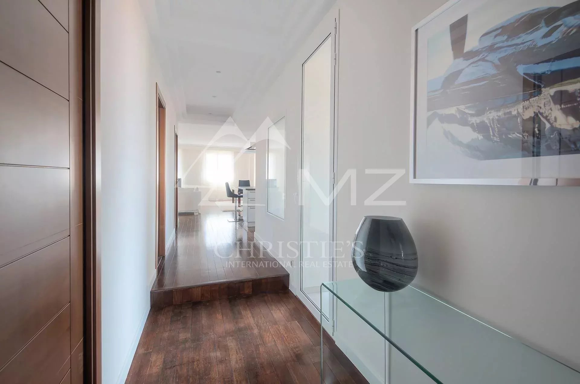 Bright hallway with dark wood floor, glass console table, and a framed landscape print along the wall.