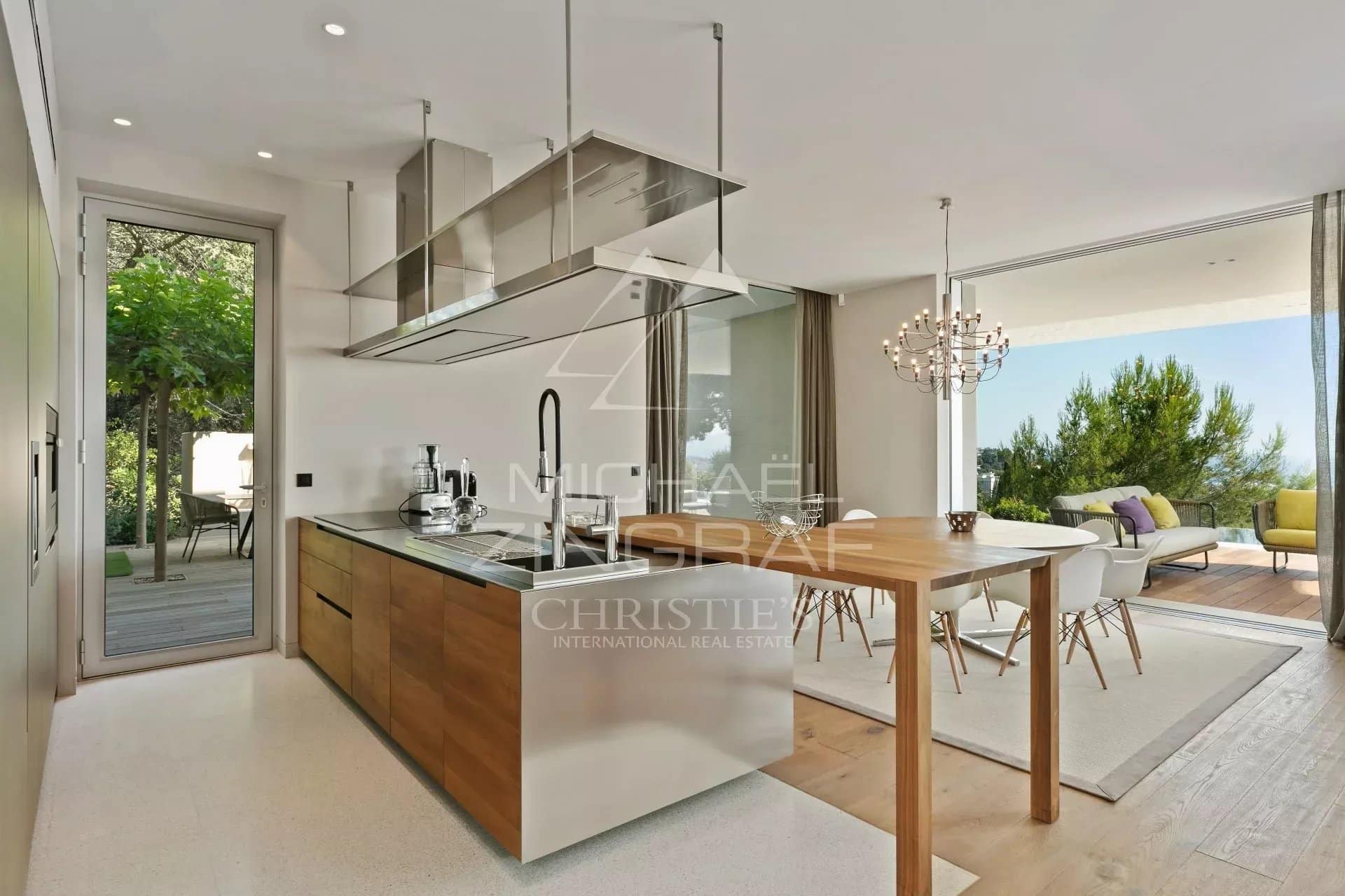 Cuisine d’une villa à Cannes Cuisine moderne avec îlot central et salle à manger, ouverte sur l'extérieur.
