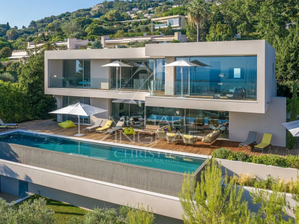 Villa moderne avec piscine à Cannes, entourée de verdure, vue dégagée.