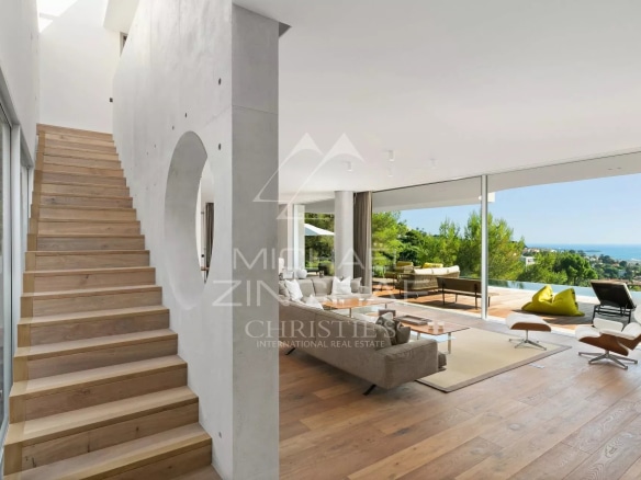 Intérieur d'une villa moderne à Cannes avec escalier en bois et salon lumineux.