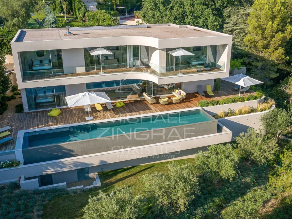 Villa moderne avec piscine et terrasse à Cannes, entourée de verdure.