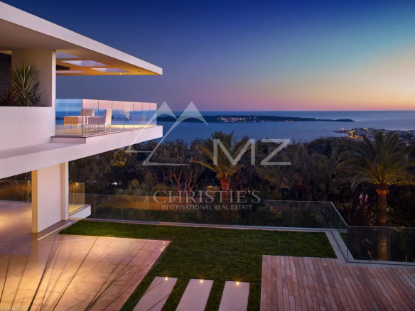 Vue d'une propriété contemporaine à Cannes avec piscine et vue sur la baie de Cannes au crépuscule.