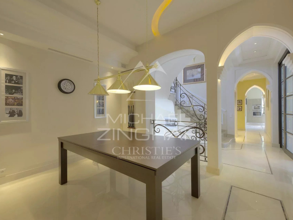 Intérieur d'un hôtel particulier à Cannes avec une table, des luminaires et un escalier décoratif.