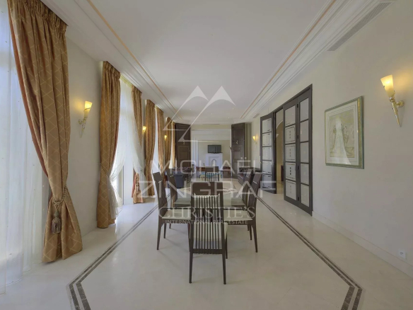 Intérieur d'un hôtel particulier à Cannes avec salle à manger élégante et baies vitrées.