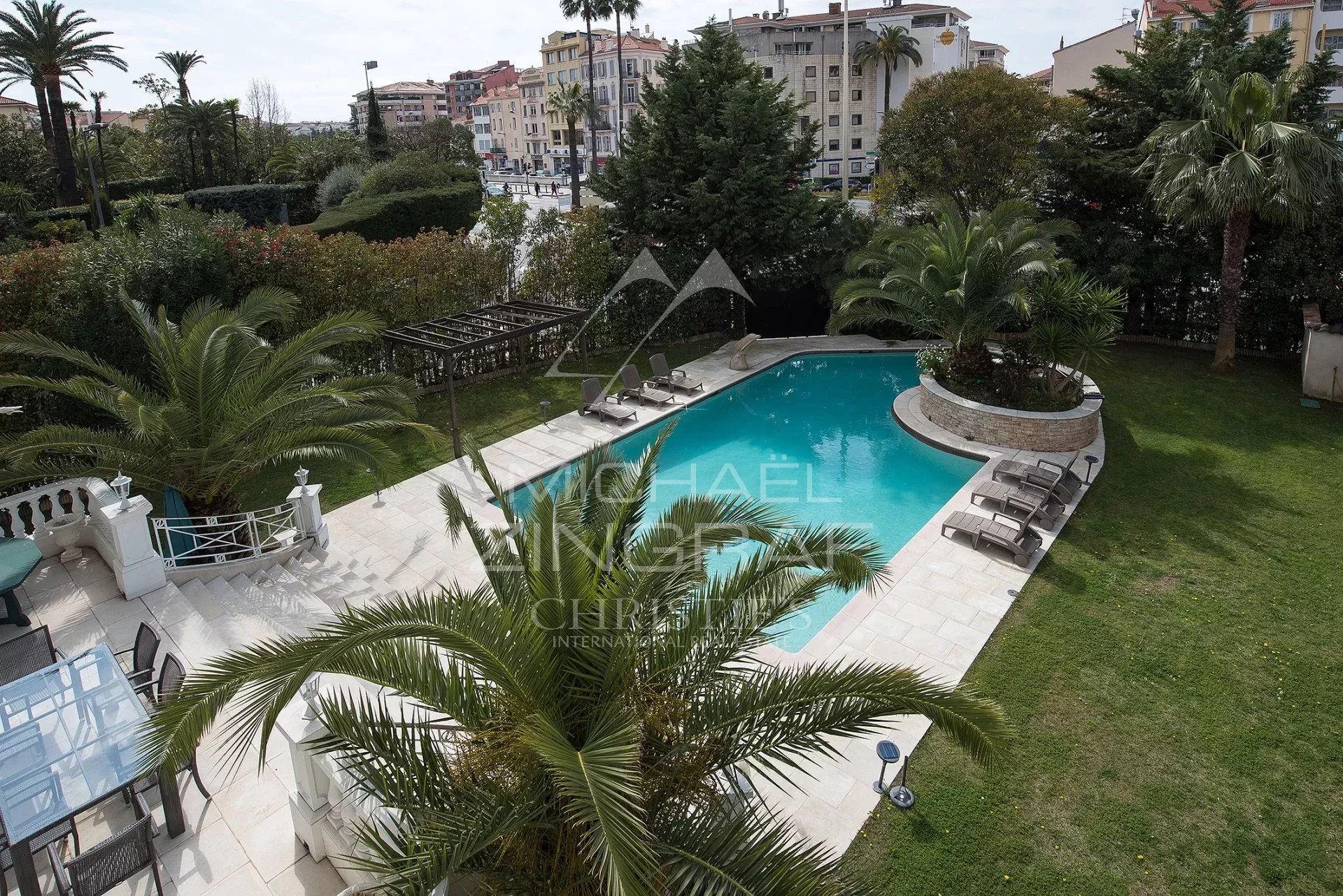 Hôtel particulier à Cannes Vue d'ensemble d'une piscine entourée de palmiers et d'un jardin dans un hôtel particulier à Cannes.