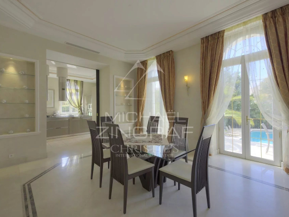 Intérieur d'un hôtel particulier à Cannes avec une salle à manger élégante et des grandes fenêtres.