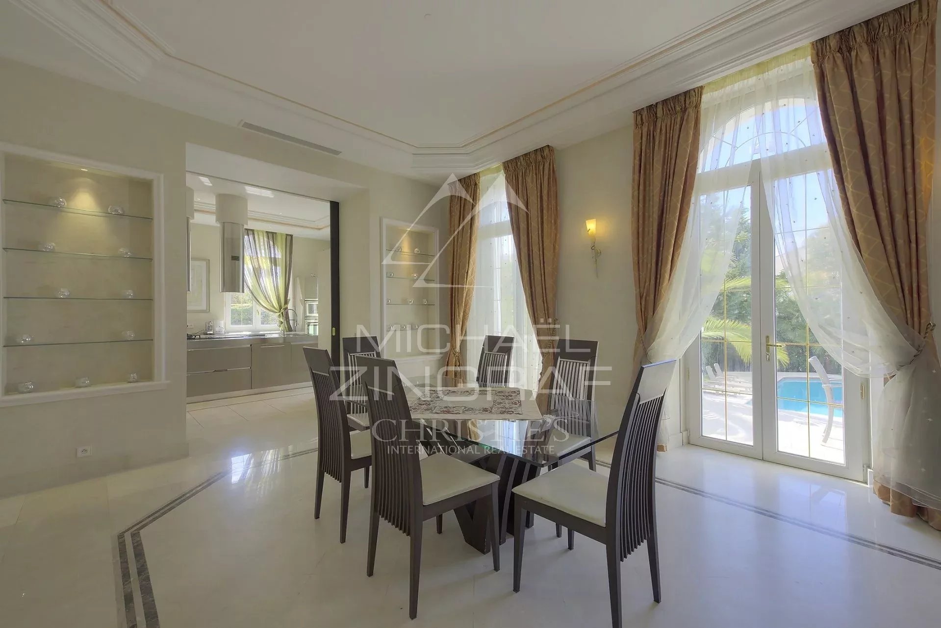 Salle à manger d’un hôtel particulier à Cannes Intérieur d'un hôtel particulier à Cannes avec une salle à manger élégante et des grandes fenêtres.