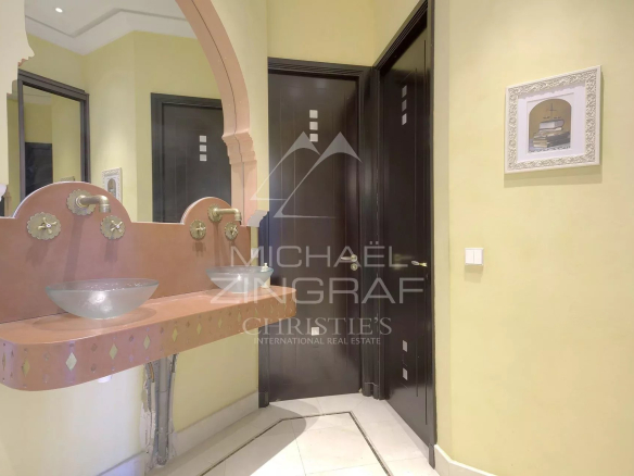 Salle de bain avec lavabo en verre et décorations murales dans un hôtel particulier à Cannes.