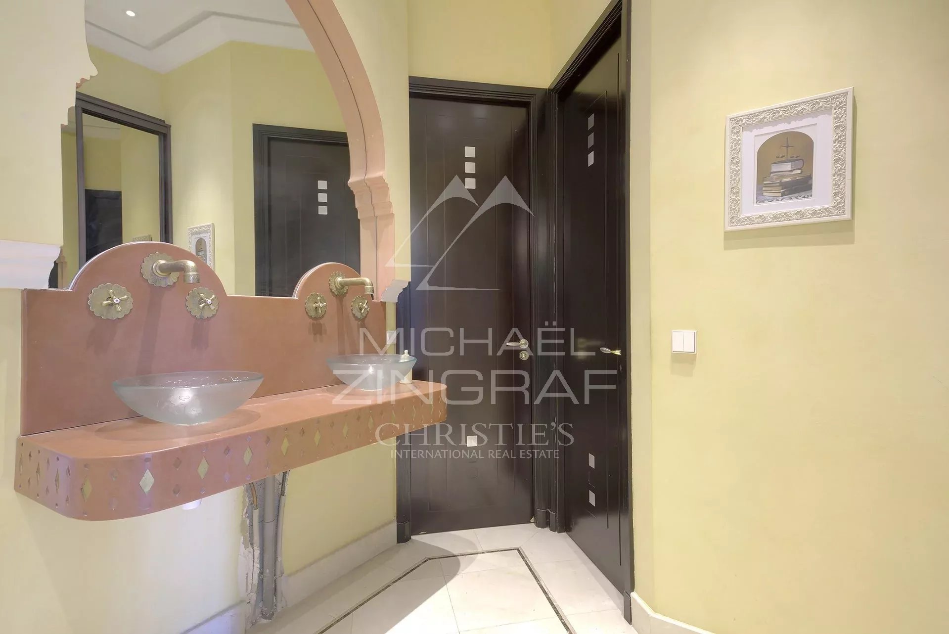 Salle de bain d’un hôtel particulier à Cannes Salle de bain avec lavabo en verre et décorations murales dans un hôtel particulier à Cannes.