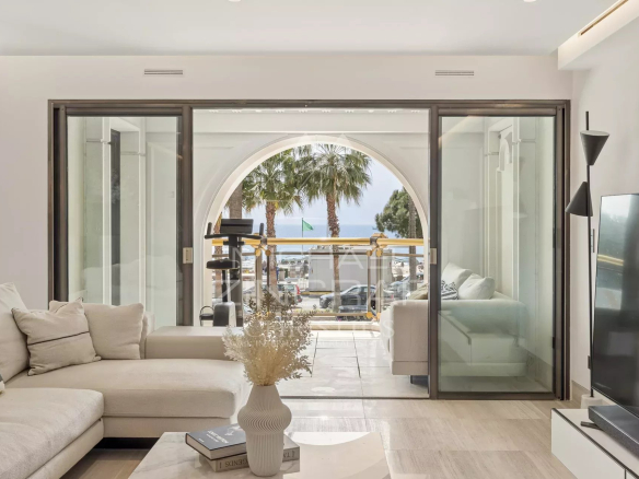 Interior of a luxury apartment with sea views in Cannes, windows open onto a balcony.