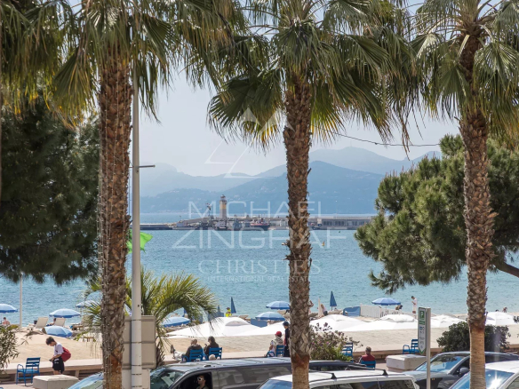 Sea view from an apartment on the Croisette in Cannes, with palm trees in the foreground.