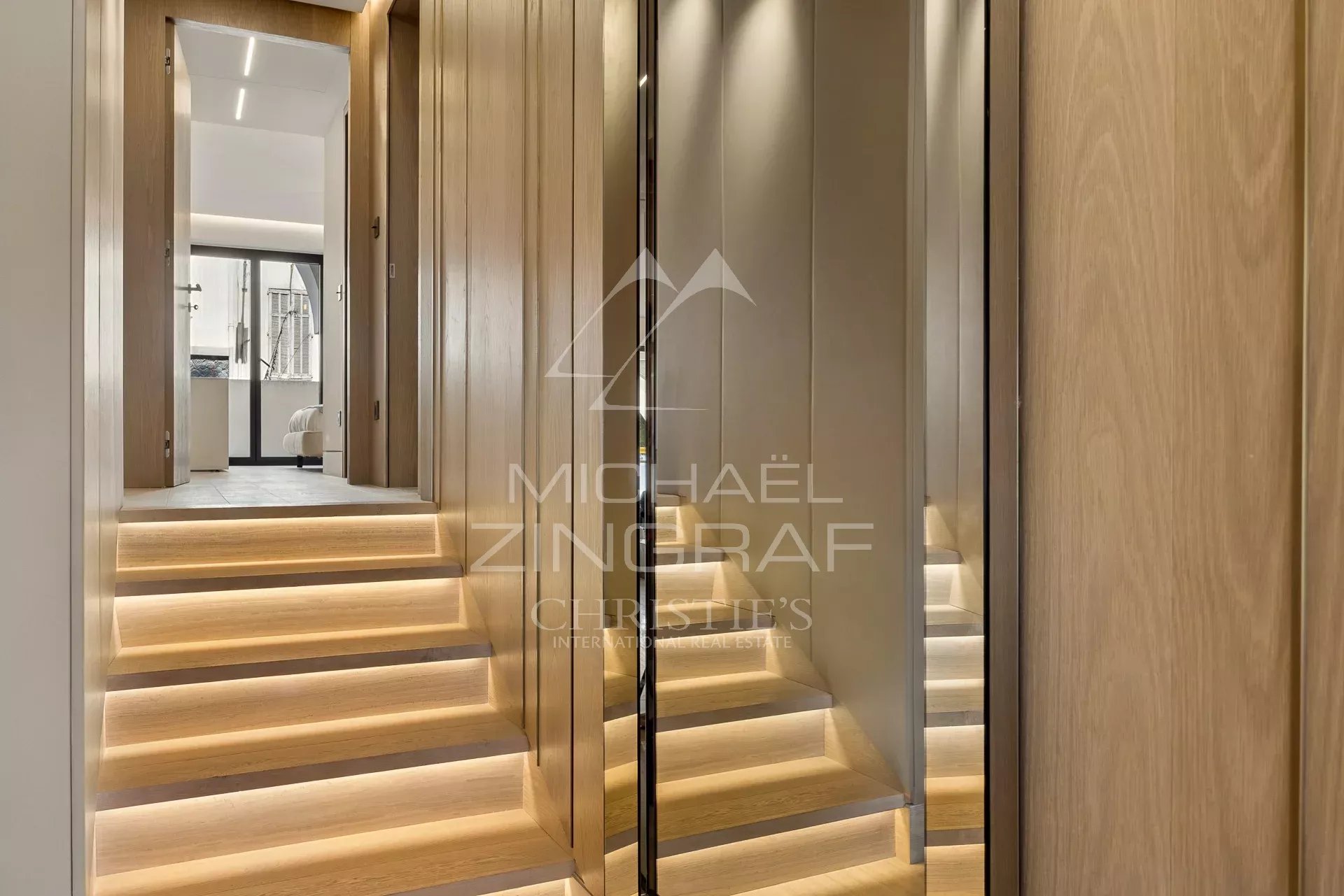 Staircase of a luxury apartment in Cannes Interior of a luxury apartment with a wooden staircase and mirrored walls in Cannes.