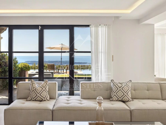 Intérieur moderne d'une villa avec vue sur la mer, salon lumineux et accès au jardin.