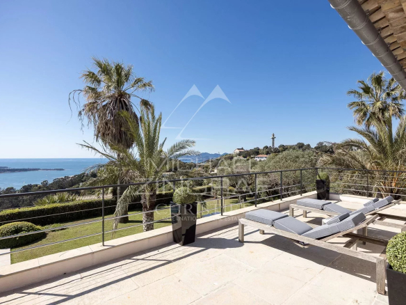 Terrasse de villa avec vue panoramique sur la mer, entourée de palmiers et de verdure à Vallauris.