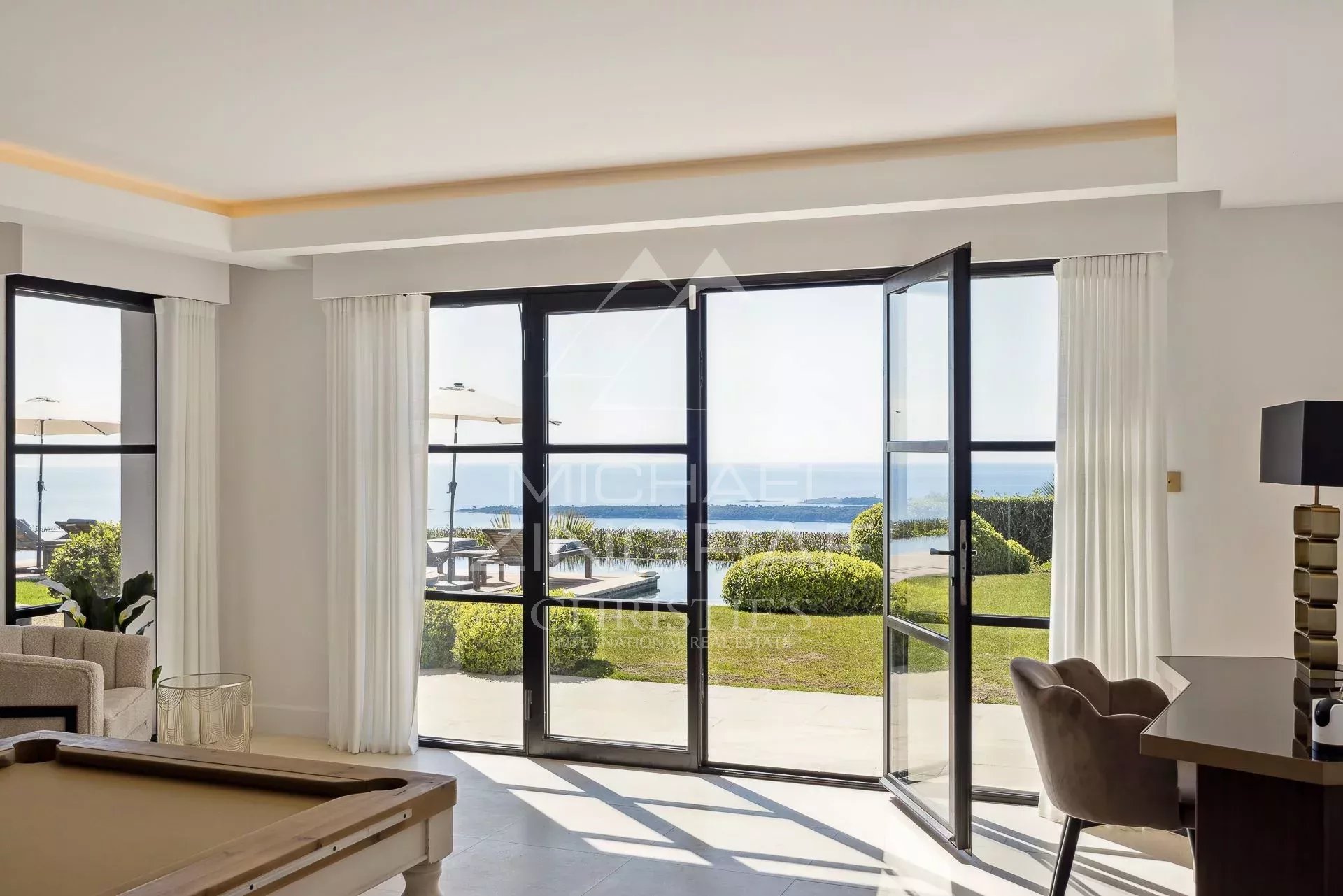 Intérieur de villa avec vue mer Intérieur d'une villa moderne avec vue panoramique sur la mer, grandes baies vitrées ouvertes.