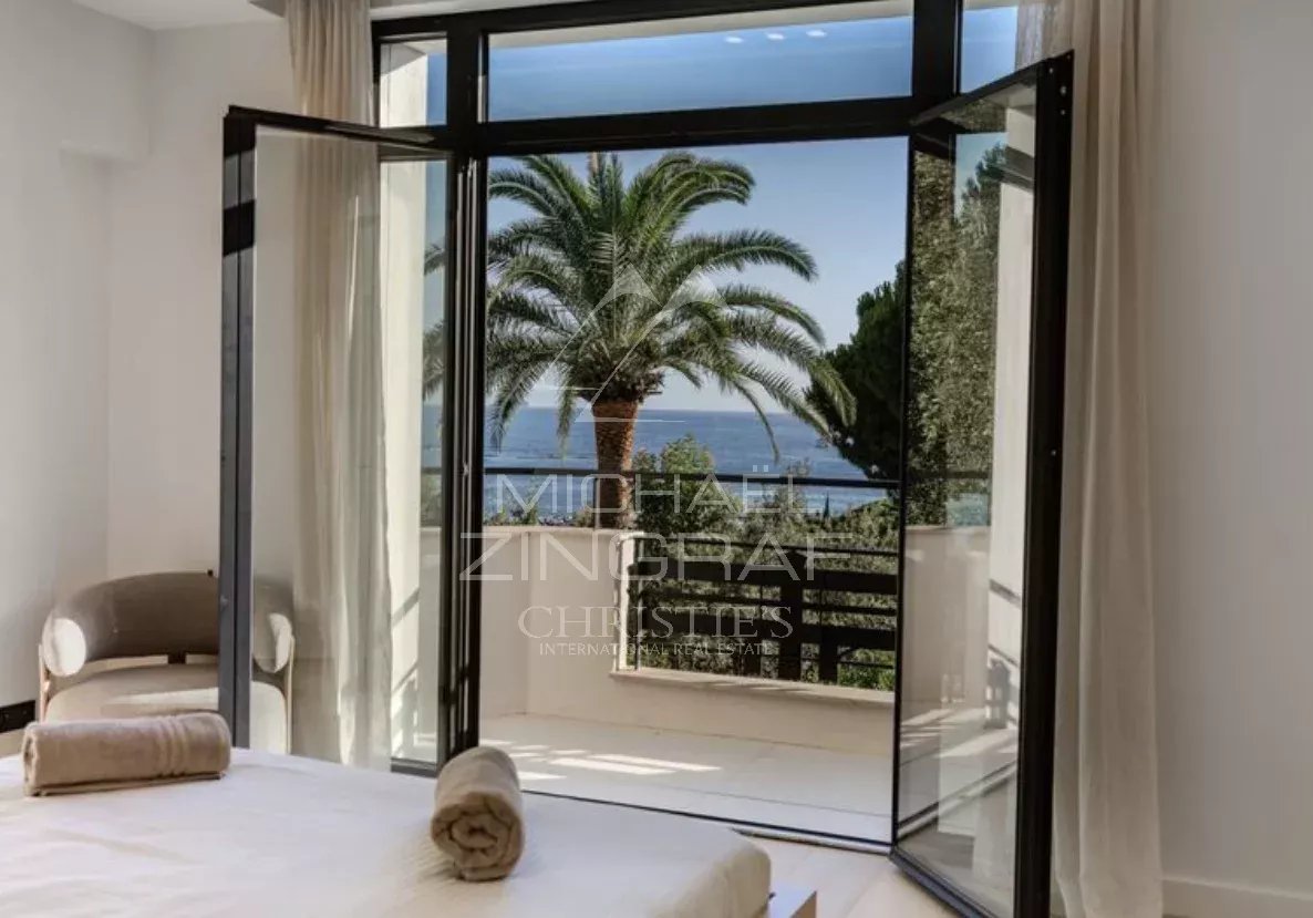 Chambre avec vue à Cap d’Antibes Vue depuis une chambre d'une villa neuve à Cap d'Antibes, avec des palmiers et la mer en arrière-plan.