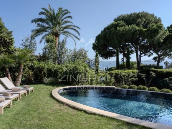 Vue de la piscine et du jardin d'une villa neuve à Cap d'Antibes avec palmiers.