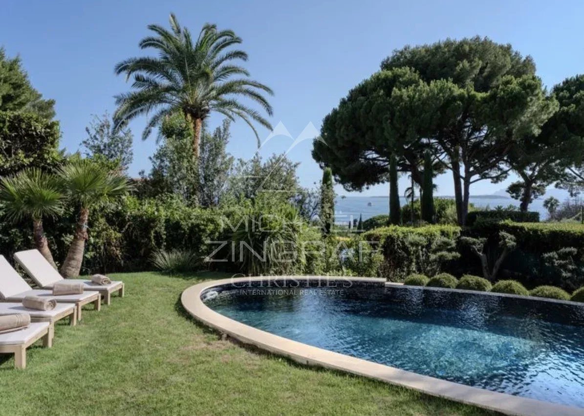 Villa neuve à Cap d’Antibes Vue de la piscine et du jardin d'une villa neuve à Cap d'Antibes avec palmiers.