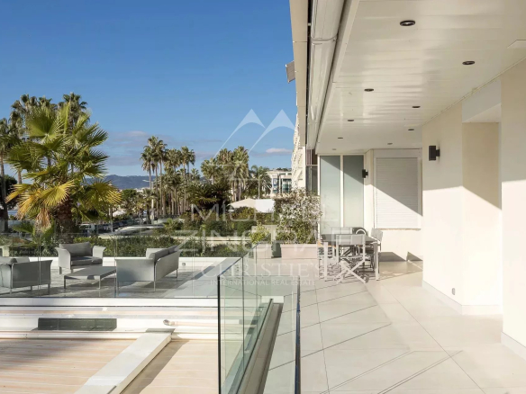 Terrace of a bright apartment in Cannes with sea view and outdoor furniture.