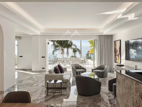 Interior of a bright, renovated apartment with sea views in Cannes, including a living room and modern armchairs.