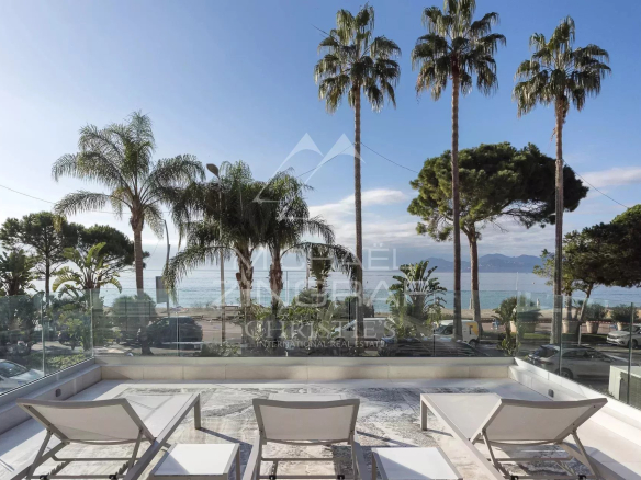 View from a terrace of an apartment in Cannes, with sun loungers and a palm tree in the background.
