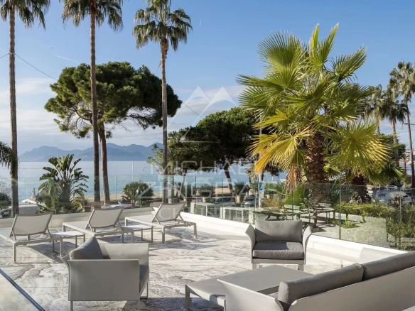 Terrace of an apartment in Cannes with views of the sea and palm trees.