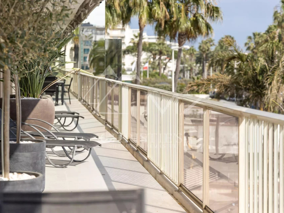 Terrasse spacieuse d'un appartement sur la Croisette à Cannes, avec chaises longues et vue sur la mer.