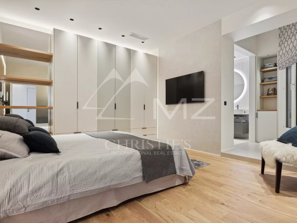 Chambre spacieuse d'un appartement de luxe à Cannes, avec lit et télévision murale.