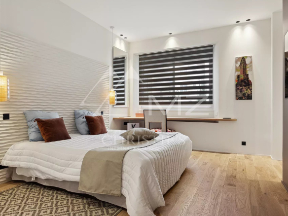 Chambre d'un appartement luxueux à Cannes avec lit, décoration moderne et éclairage doux.
