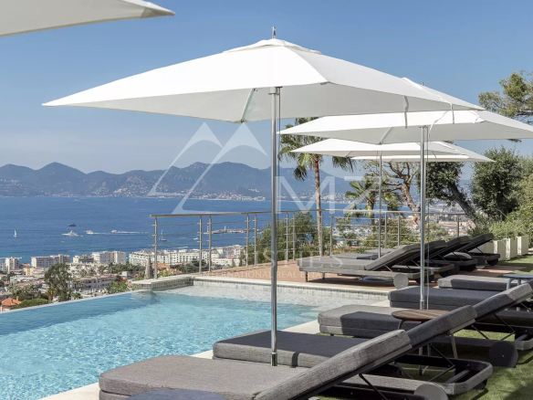 Vue panoramique sur la mer depuis une villa avec piscine et transats à Cannes.