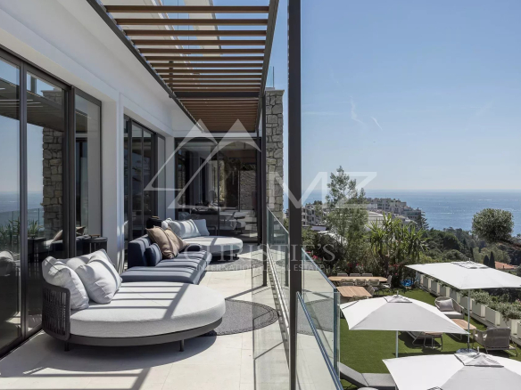 Vue panoramique depuis une terrasse d'une villa contemporaine à Cannes, avec mer en arrière-plan.